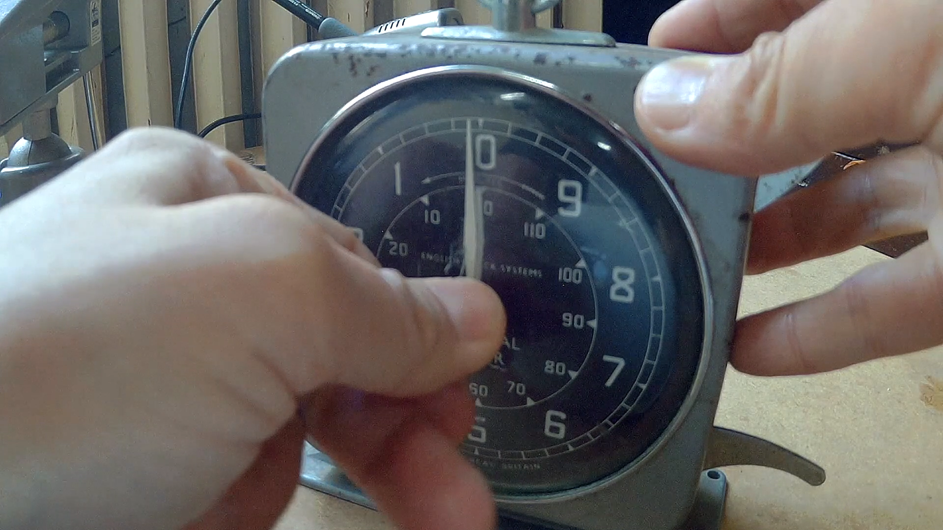Close up image of an old, industrial looking analogue clock being set with two hands from a shimatsu performance by Ryoko Akama